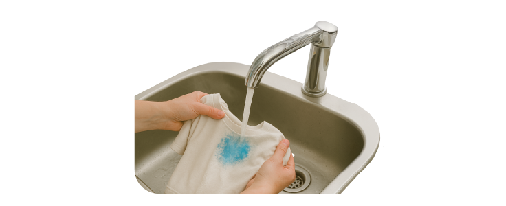Prenda siendo enjuagada con agua caliente en un fregadero