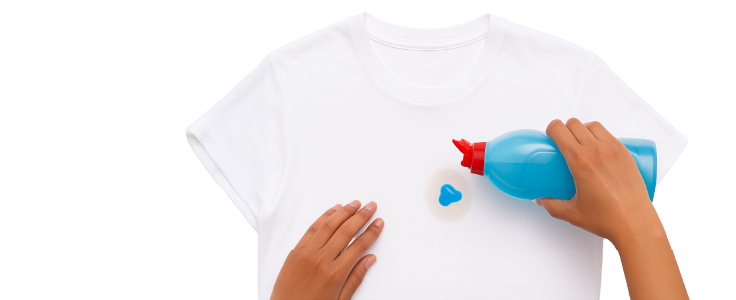 Manos aplicando detergente sobre camiseta blanca