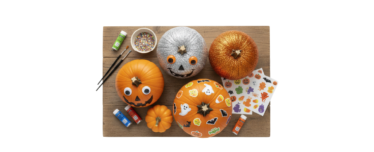 Varias calabazas decoradas con pintura, stickers y escarcha sobre una mesa